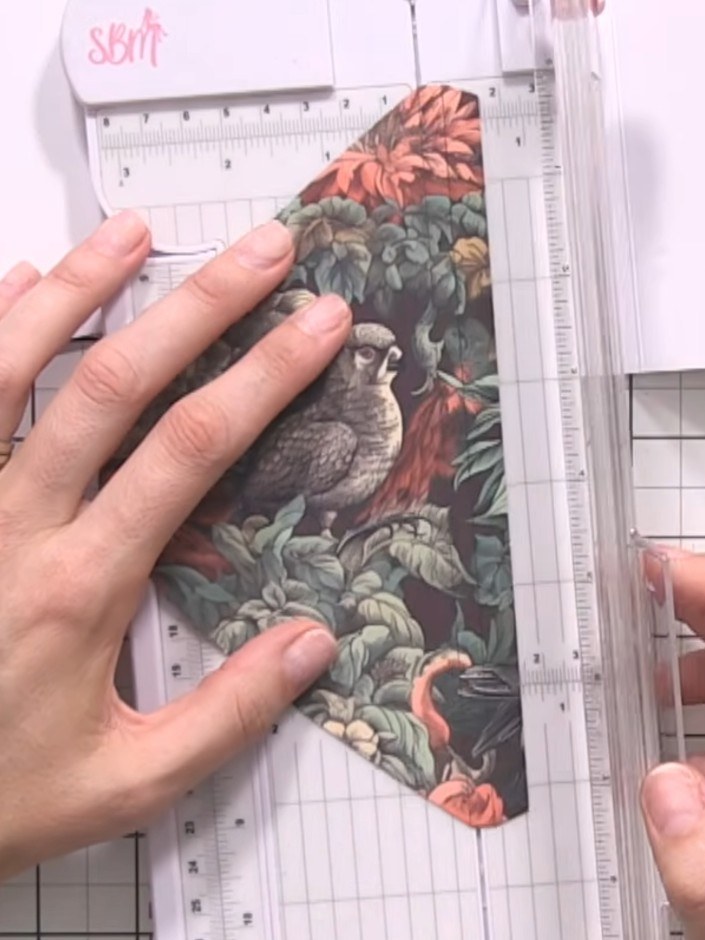 Step 5: Select a flap closure piece with the bird design and place it in your paper trimmer. Score along the marked li
