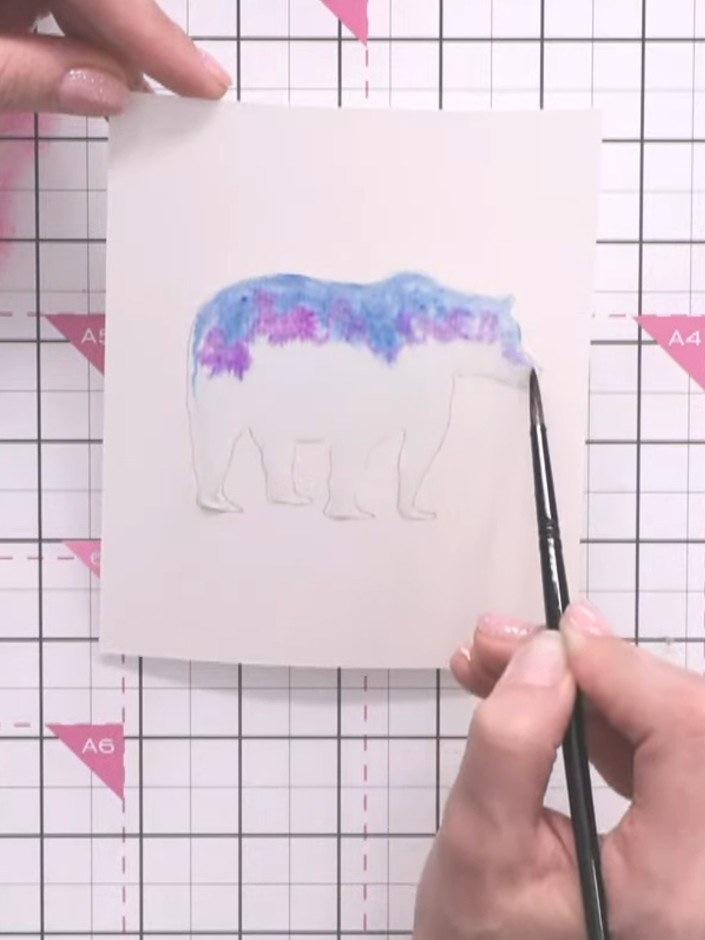 Step 5: Using a paintbrush, add pink and purple dye inks to different areas of the wet bear silhouette. Allow the colo