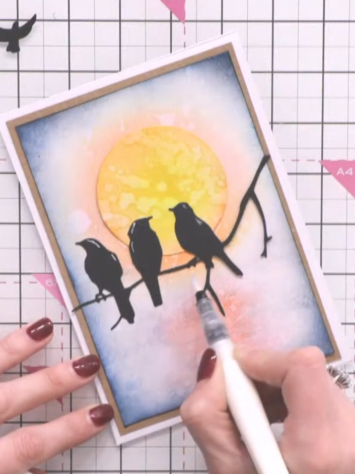 Step 12: Add shimmer pen details to the water area below the birds for sparkle. Finish the card by adding a sentiment o