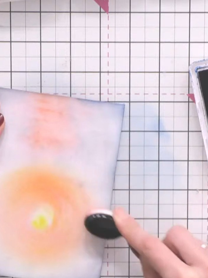 Step 7: Spray water onto your fingers and gently dab and blend the inked colours on the background panel. Use a tissue