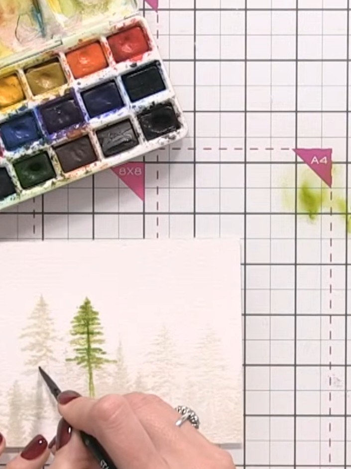 Step 7: Continue wetting and painting each remaining tree with green watercolour, varying the intensity of the green t