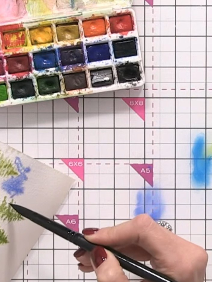 Step 9: Apply blue watercolour into the wet background around your trees, allowing the colours to blend naturally and 