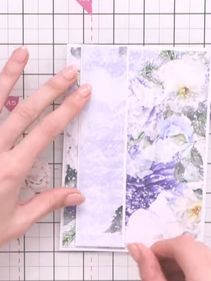 Step 7: Adhere the white stamped panel flat to the card base. Layer the fussy-cut purple flowers and green leaves on t
