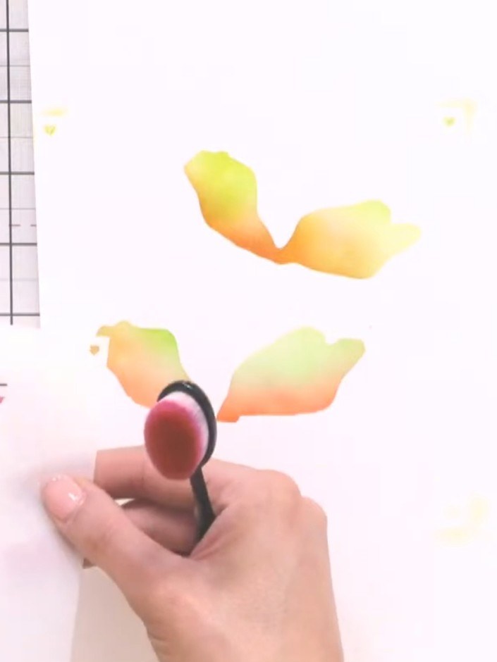 Step 6: Using stencil three, apply pink and purple ink tones to the card to build depth and add colour variation to th