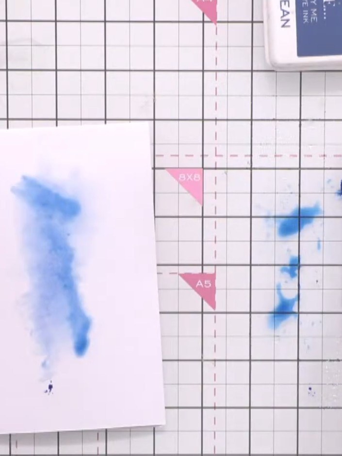 Step 2: Use an ink pad lid to add additional colour lines into the wet blue ink on your card, creating texture and dep