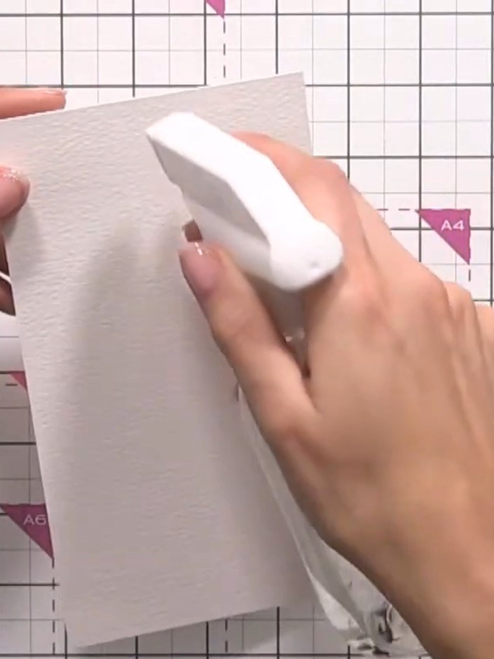 Step 2: Spray water onto the watercolour card in the middle area and tilt to distribute the water evenly across the su