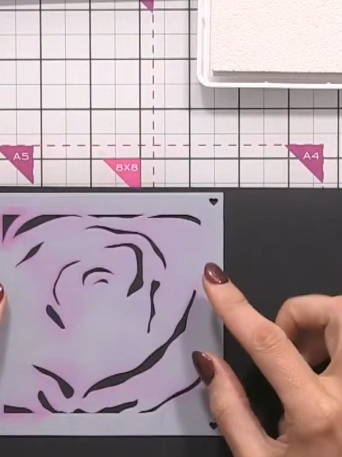 Step 1: Place the rose stencil on your black card and secure it in position. Apply black ink through the stencil using