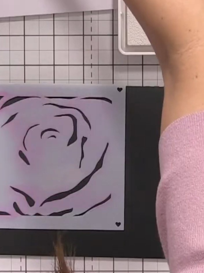 Step 2: Position the rose stencil on the black card and apply pink ink lightly through the stencil to build up the ros