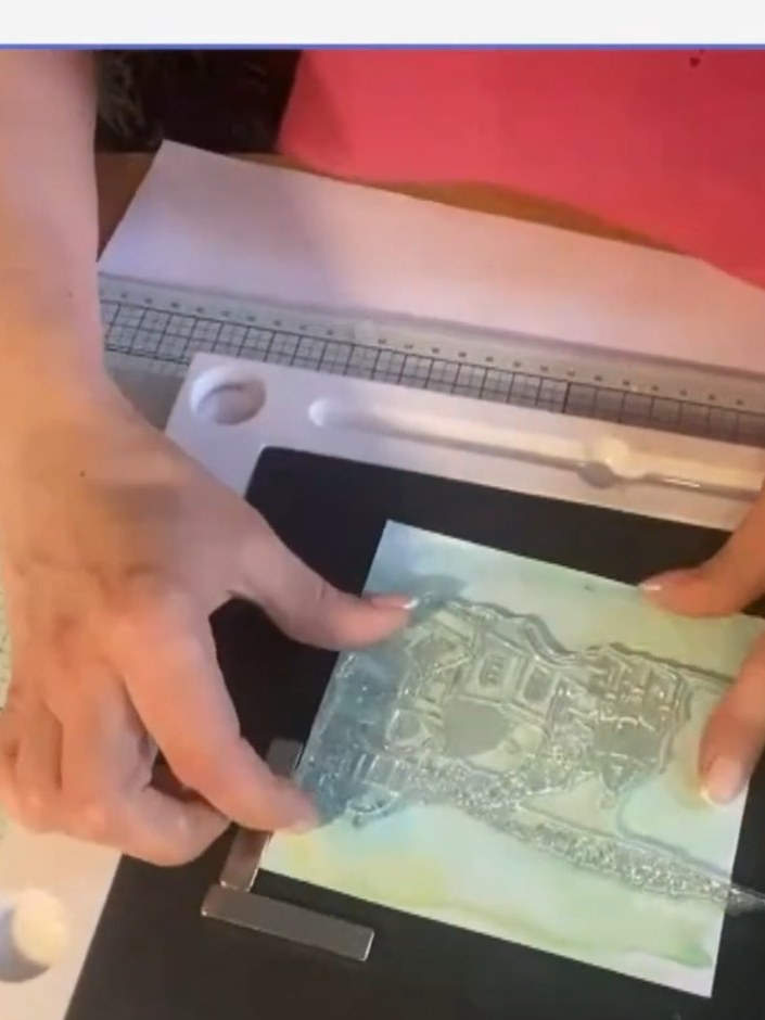 Step 2: Using your stamp tool with broken china and mermaid lagoon distress oxide inks, stamp the rooftop scene from t