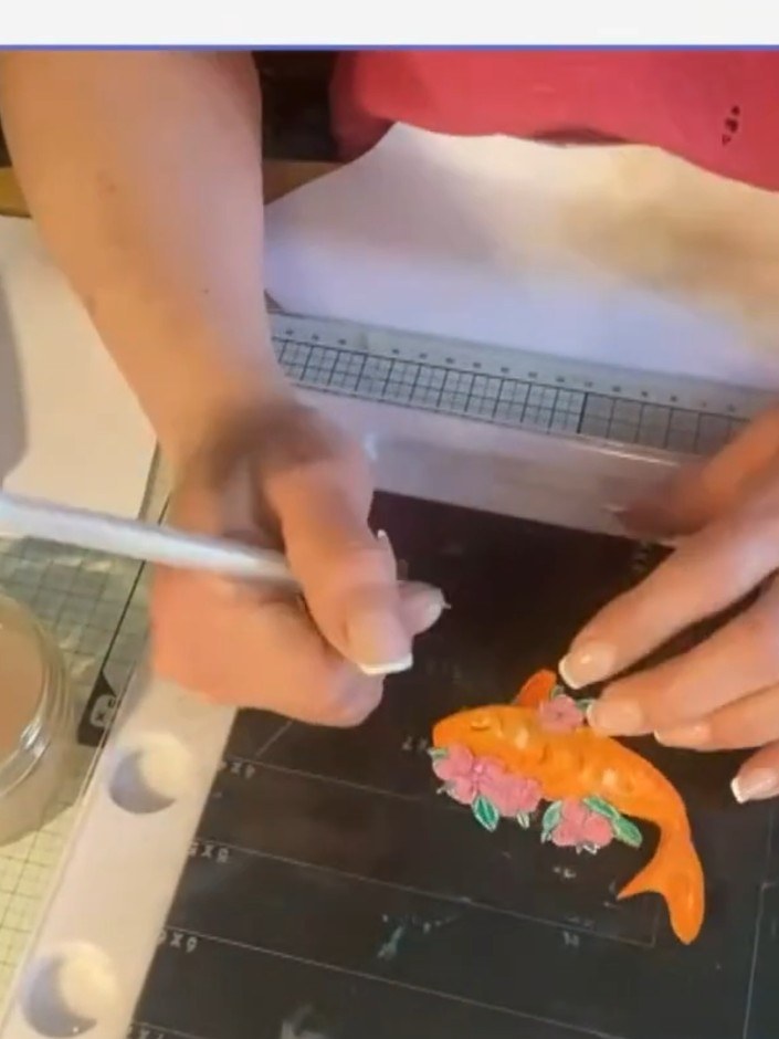 Step 9: Use a white gel pen to add fine details to the fish, including eyes and highlights on the body.