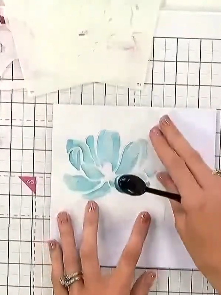 Step 3: Remove the first stencil and position the second stencil over the card. Apply a second turquoise ink colour us