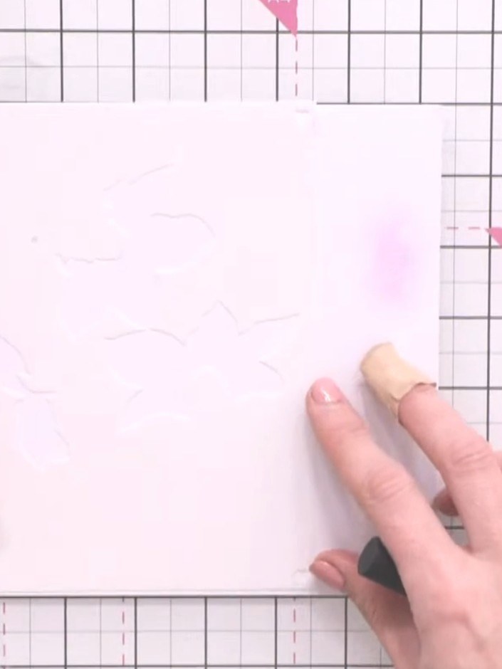 Step 6: Position stencil number one over the white card piece. Using a blending brush, apply light pink ink through th