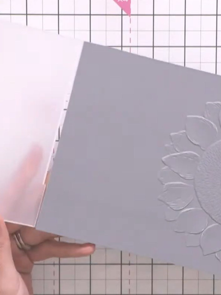Step 3: Observe the embossed half-crest sunflower design on the grey card. The embossing creates a raised floral patte