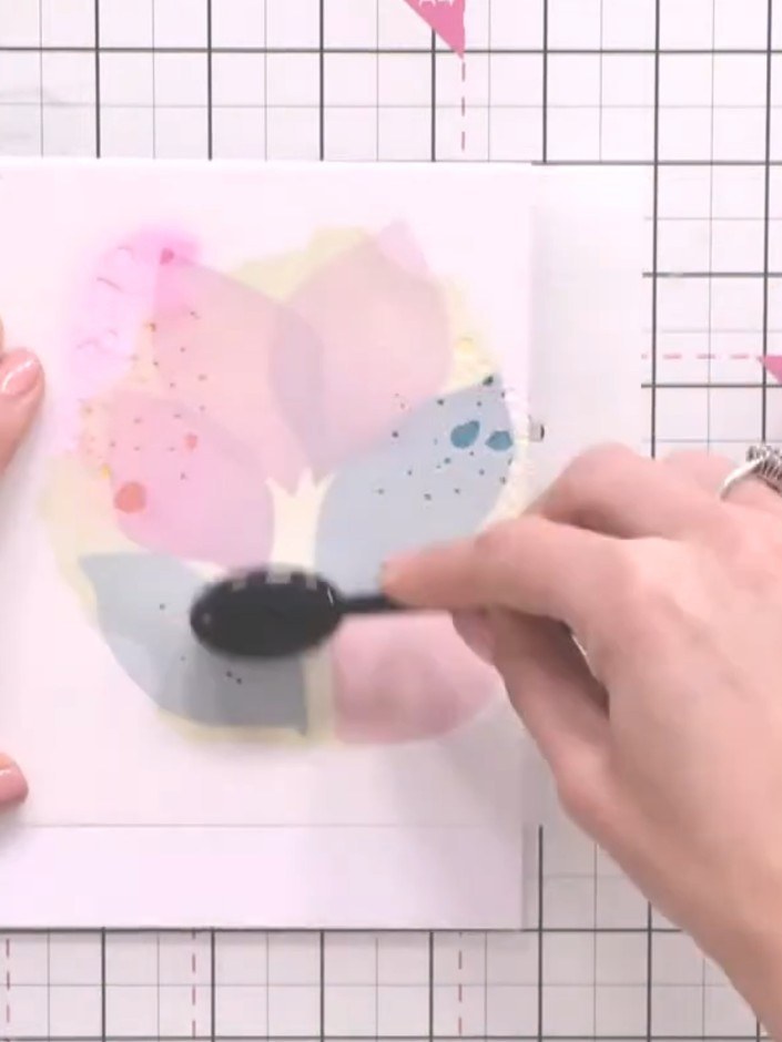 Step 6: Use the splat stencil to add artistic splatter details across the watercolour design. Position the stencil in 