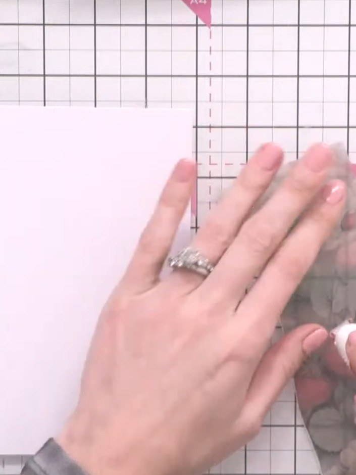 Step 4: Using a tape pen, adhere the vellum sheet to one side of the pink card base. Apply the adhesive carefully alon
