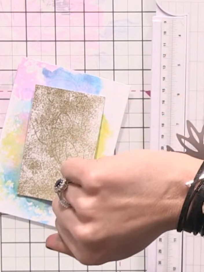 Step 6: Platziere das goldene Glitzer-Panel mittig auf der Karte mit dem Aquarell-Hintergrund und klebe es fest.