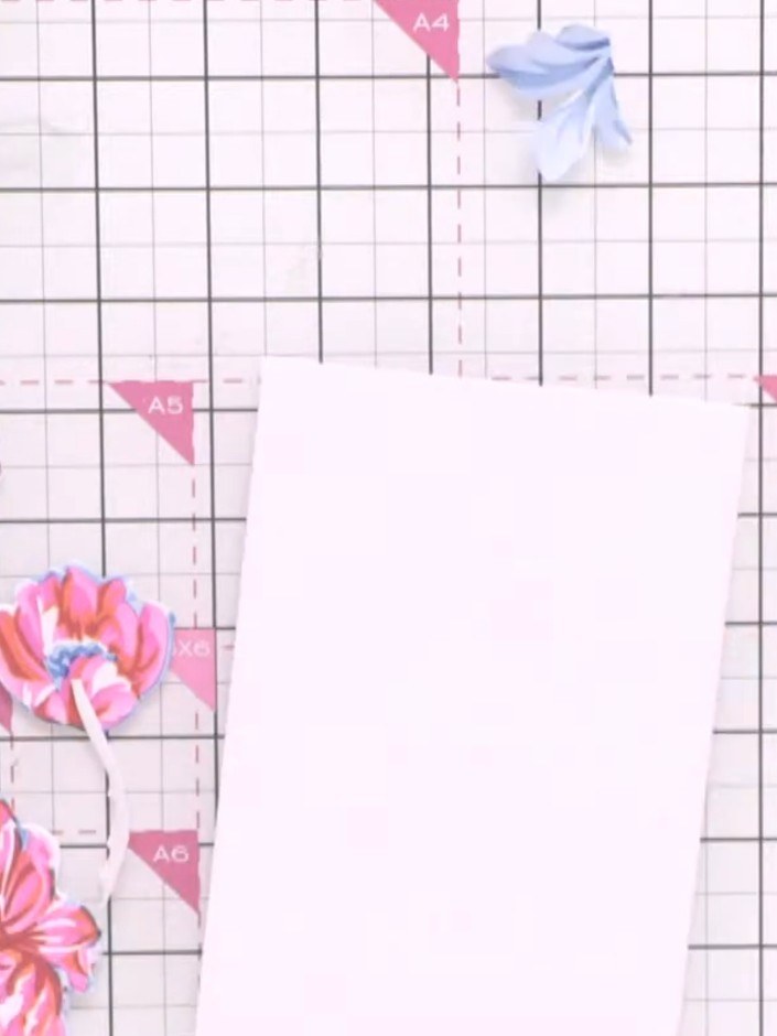 Step 9: Arrange the cut-out flower pieces around the edges of a white card base to create a decorative frame. Use low-