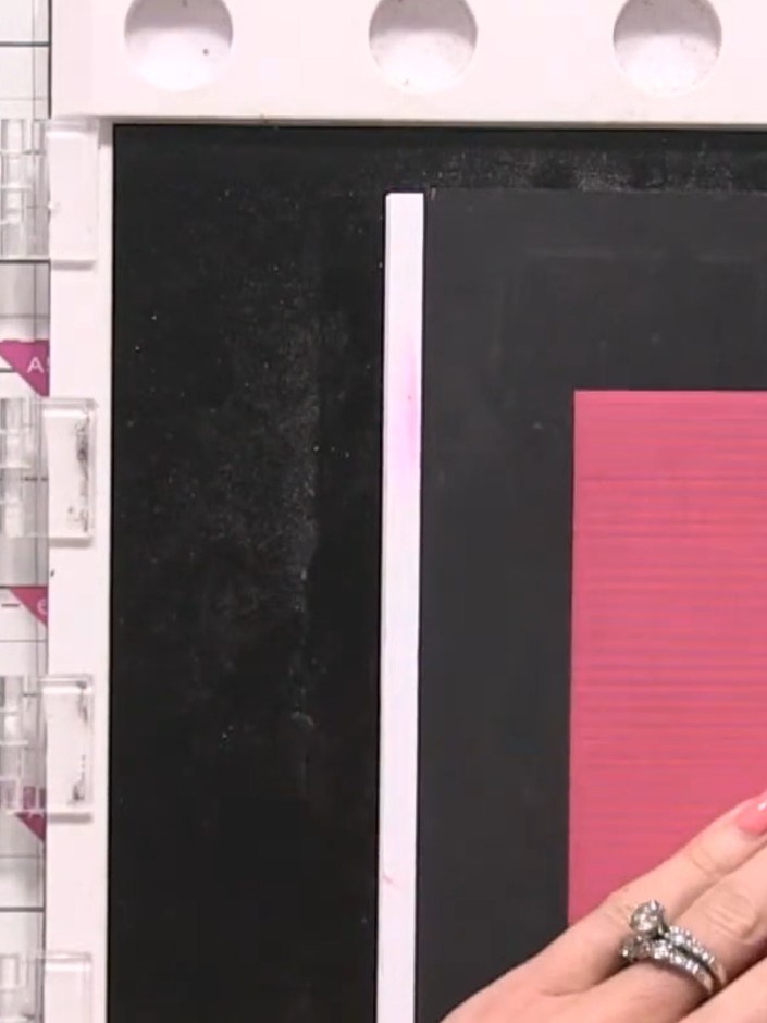 Step 8: Position each pink strip carefully on the black card, ensuring the poppy design lines up continuously across t