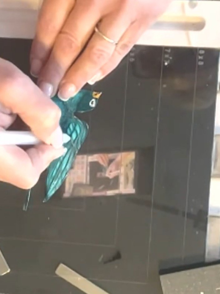 Step 6: Use a white gel pen to trace over the existing lines of the teal bird design, following the printed artwork wi