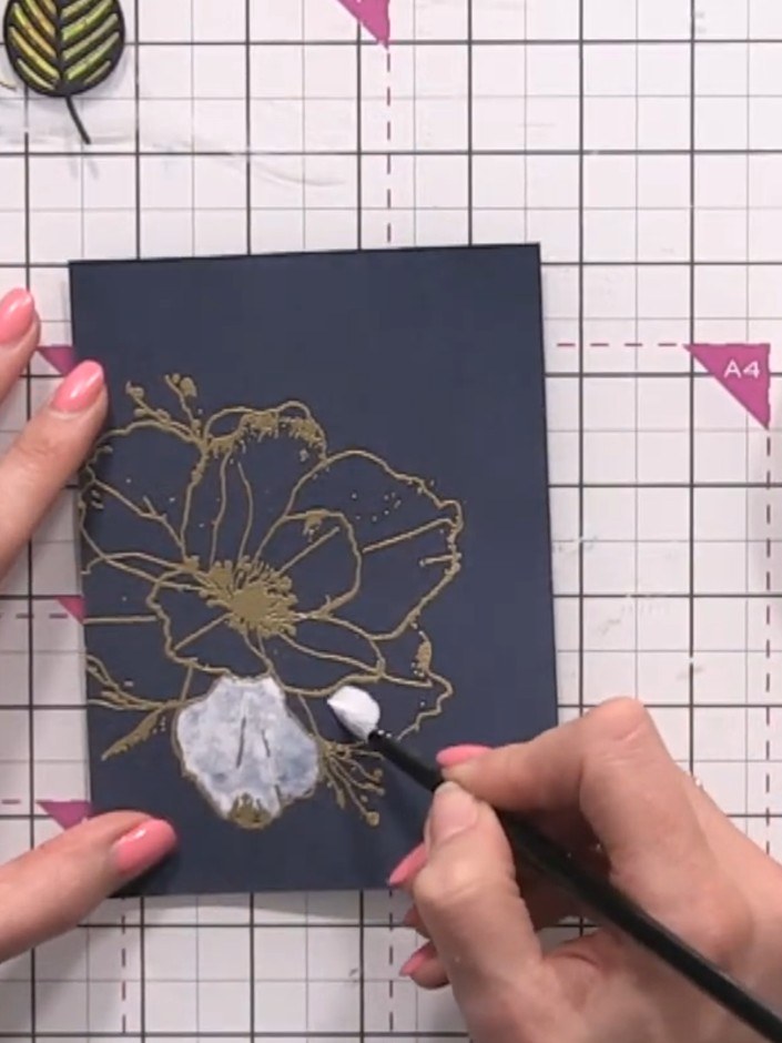 Step 7: Paint the entire flower with the white ink mixture, carefully staying within the embossed gold lines. Use a pa