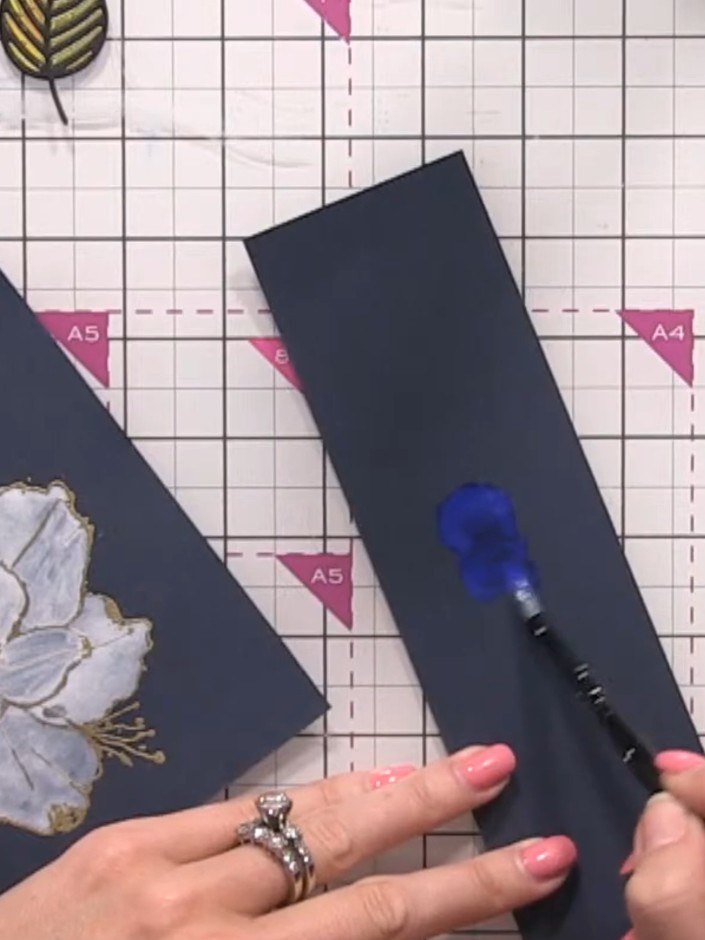 Step 9: Pick up blue watercolour paint with a wet brush and apply it to a piece of navy cardstock, creating a wash of 