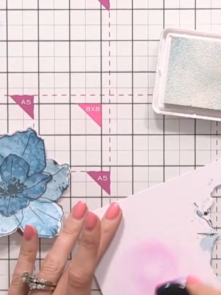 Step 11: Using a brush or sponge, apply white ink around the edges of the blue flower to create highlights and enhance 