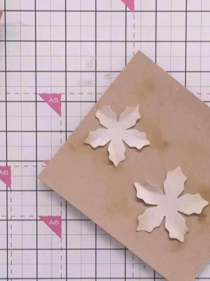 Step 1: Start with a 5x7 inch (approximately A5) kraft card blank as your base. Position white die-cut poinsettia flow