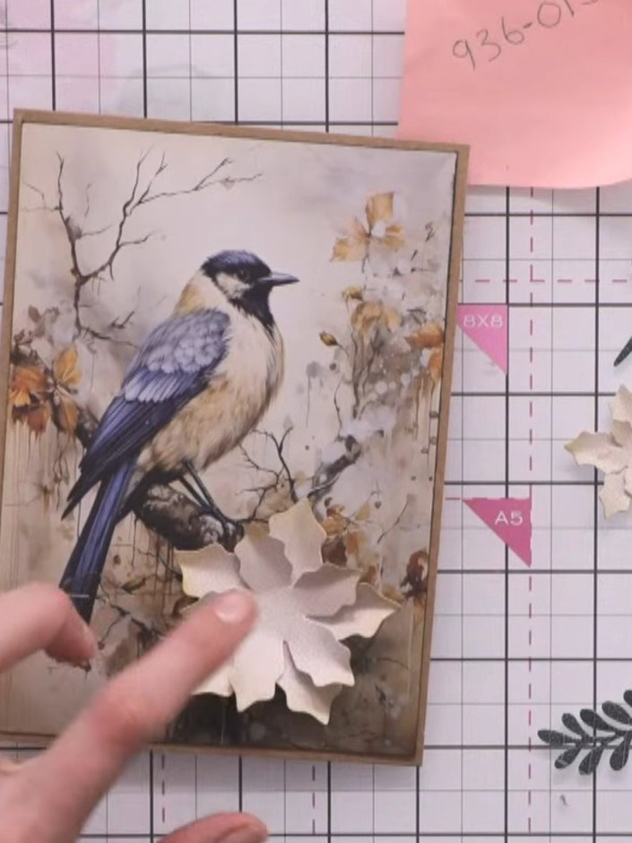 Step 10: Adhere all floral elements to the card using glue. Place some flowers flat against the surface and lift others