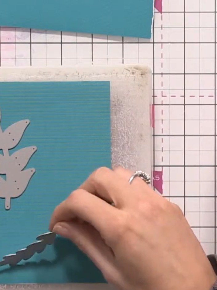 Step 3: Arrange the leaf-shaped dies from your set onto the teal card, spacing them out to create an attractive compos