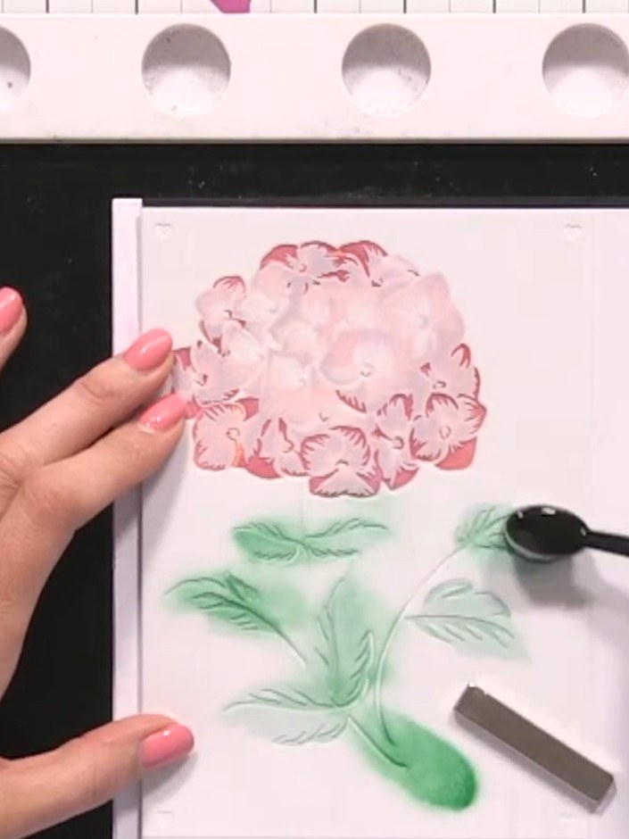 Step 8: Nimm alle Schablonen vorsichtig ab – und schon kommt dein geschichtetes Motiv mit rosa Blüte und grünen Blättern zum Vorschein.