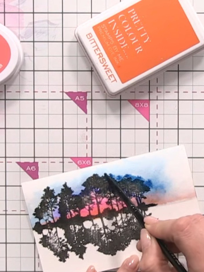 Step 10: Using a water brush or wet paintbrush, dampen the bottom portion of the card below the stamped trees to create