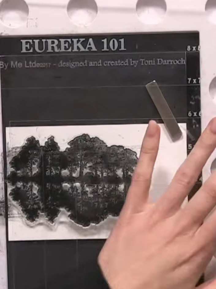 Step 3: Stamp the tree silhouette image onto the white card panel, positioning it off to one side to create a landscap