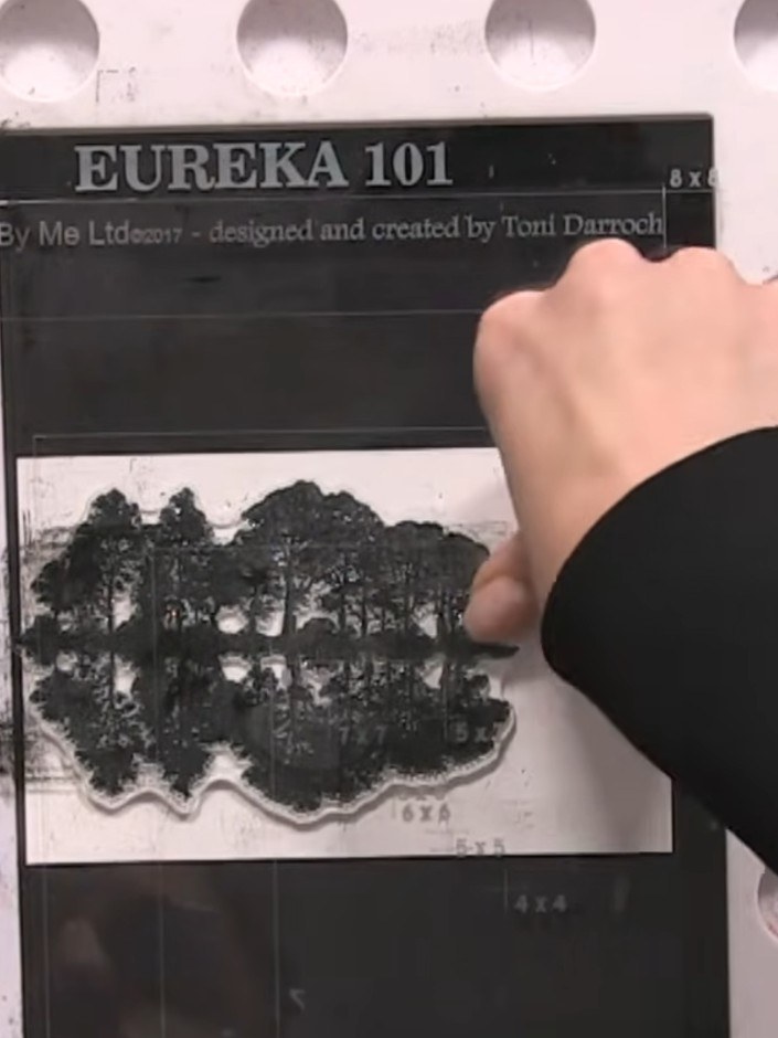 Step 4: Carefully lift the stamp away from the card to reveal the tree image with its reflection printed below, creati