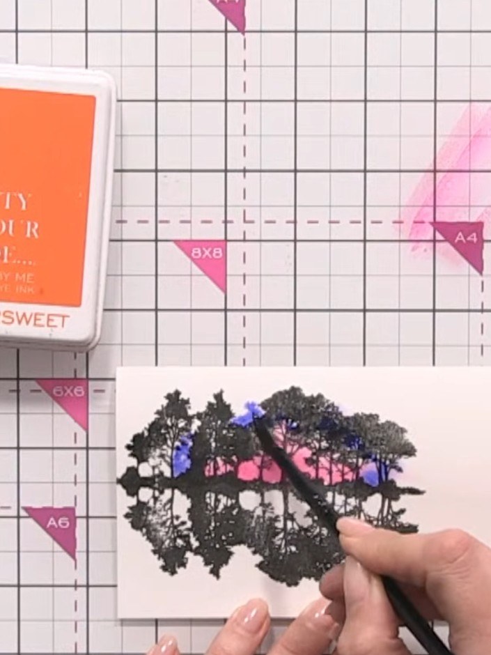 Step 7: Using a brush, blend blue and teal ink around the pink areas of the sky, creating a smooth transition between 