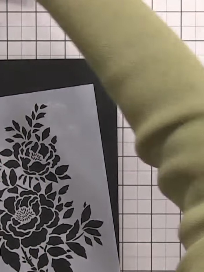 Step 1: Position your floral stencil on black card. Using a blending brush, apply white pigment ink through the stenci