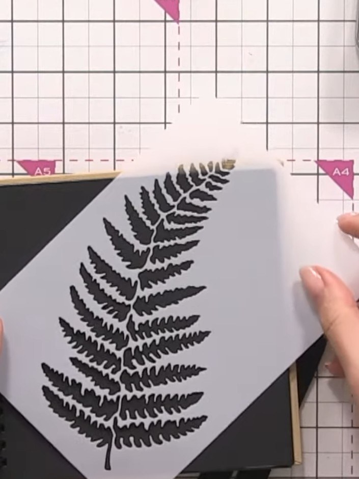 Step 1: Place the fern stencil on black card. Apply white ink pad through the stencil using a blending brush, working 