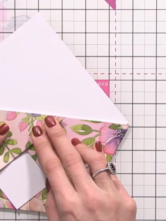 Step 6: Fold the bottom right corner of the floral paper up to align with the top edge, creating a symmetrical triangu