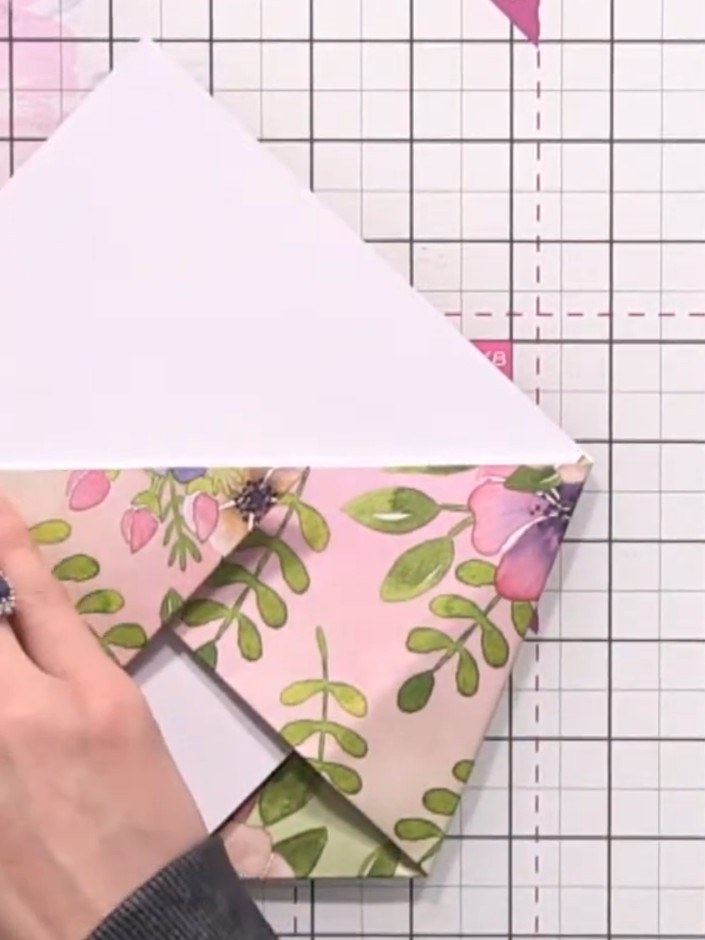 Step 7: Öffne die Faltungen wieder, damit die Tasche im Inneren zum Vorschein kommt. The floral patterned paper should now show a square pocket form