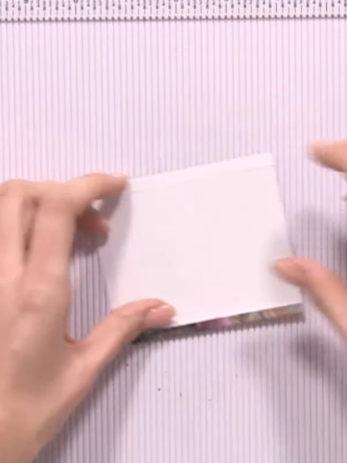 Step 4: Fold all four edges of the white card inward to create your pocket shape, creasing each fold firmly with your 