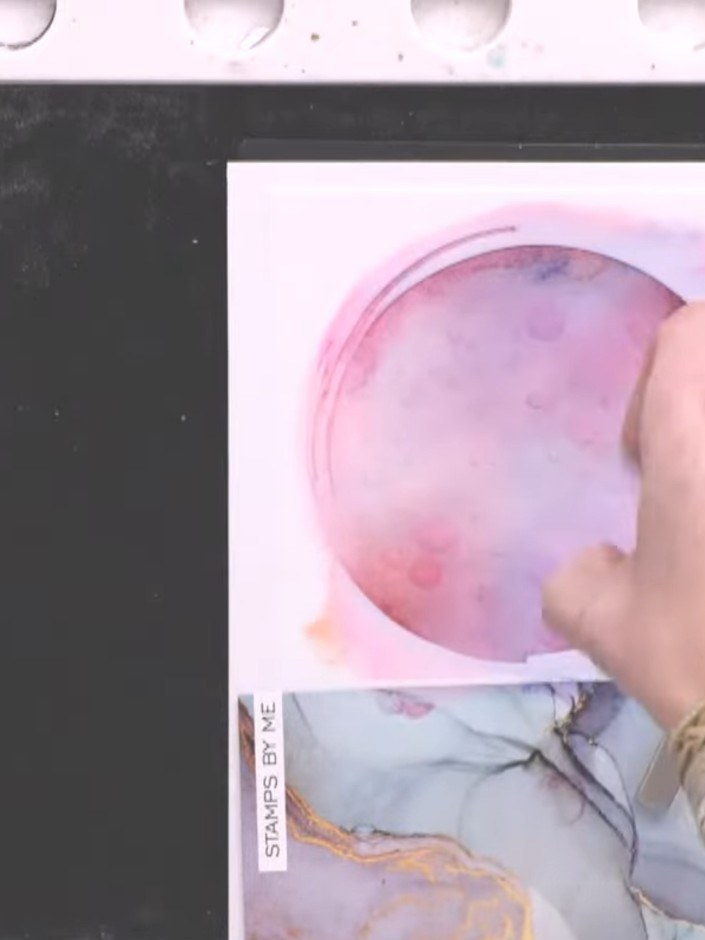 Step 7: Create a puddle of water on your hand and flick it onto the inked stencil circle to blend the pink and purple 
