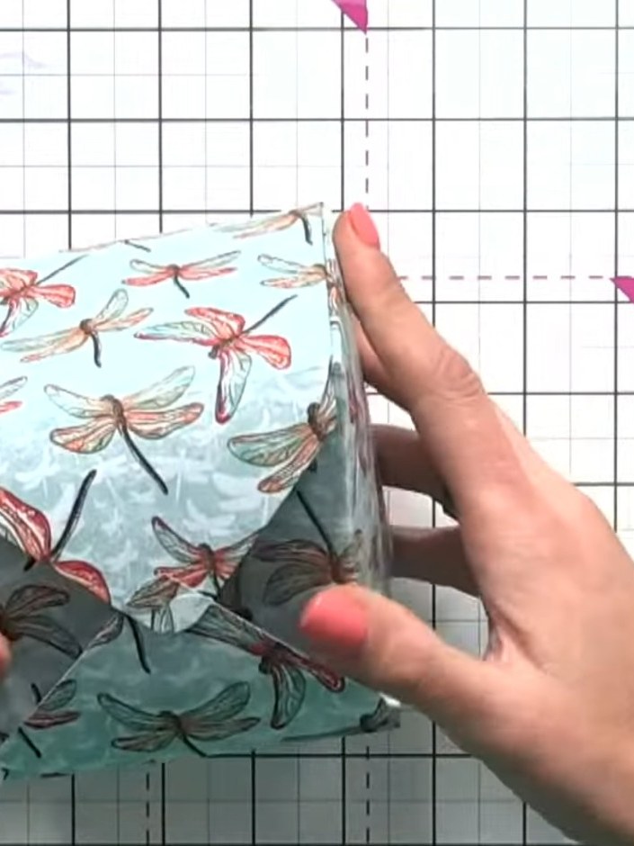 Step 12: Fold up all four sides of the box, manipulating the paper gently to form the box shape. The dragonfly patterne