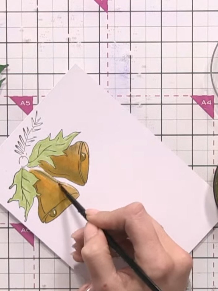 Step 12: Using a wet brush, drag the gold ink across the coloured bells to blend it smoothly over the surface. Allow th