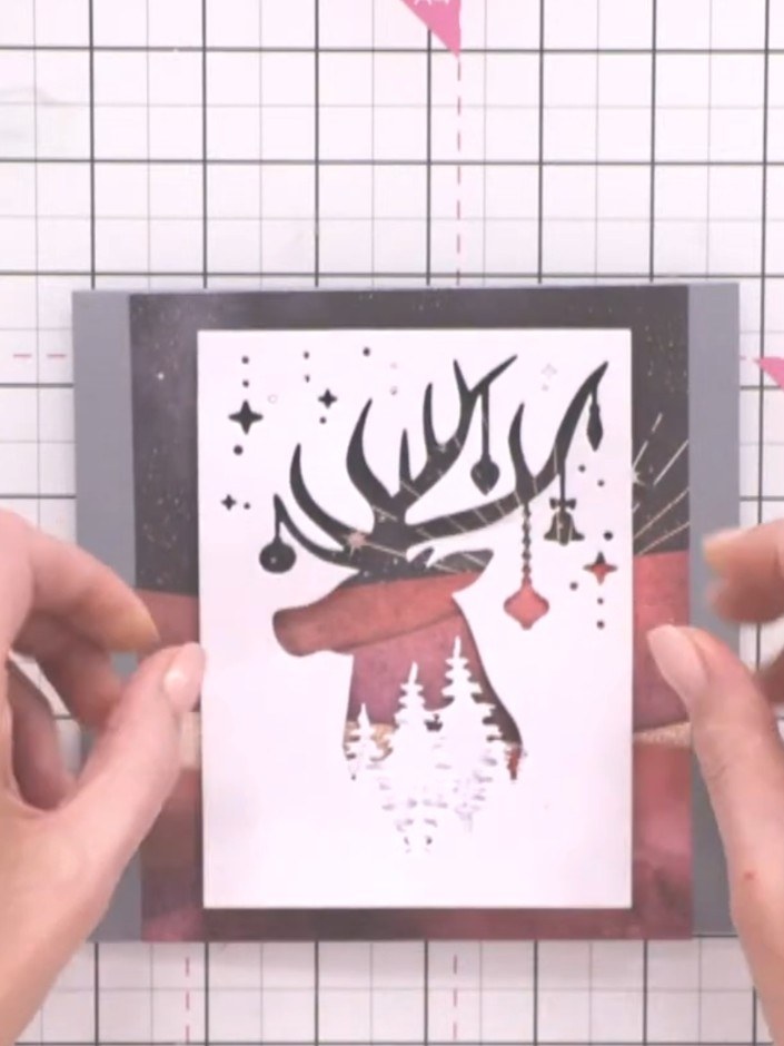 Step 9: Add optional embellishments such as glitter glue or sparkle accents to the tree lines, deer silhouette, or sen
