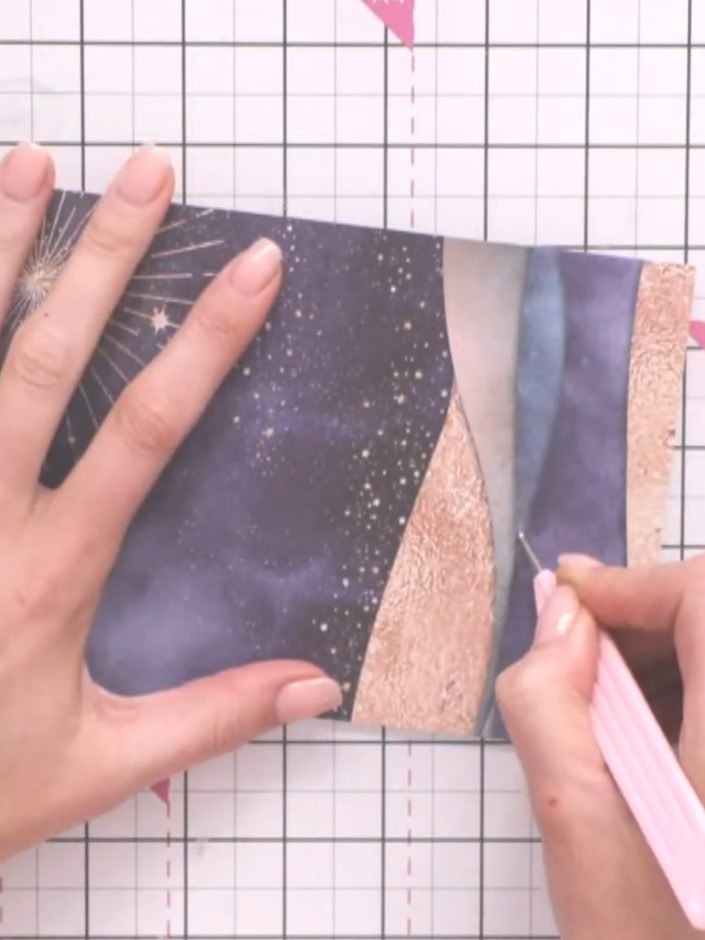 Step 2: Using a craft knife, carefully cut along each hill line on the patterned paper to create negative space cutout