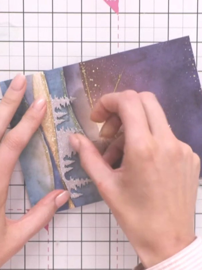 Step 5: Position a second tree line piece at a different height on your card, overlapping the first. Trim the piece to