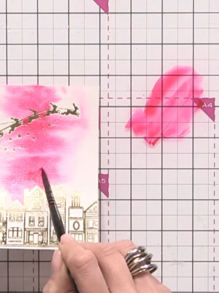 Step 4: Add pink watercolour to the sky area above the buildings, pouncing the colour onto the foiled areas. The foil 