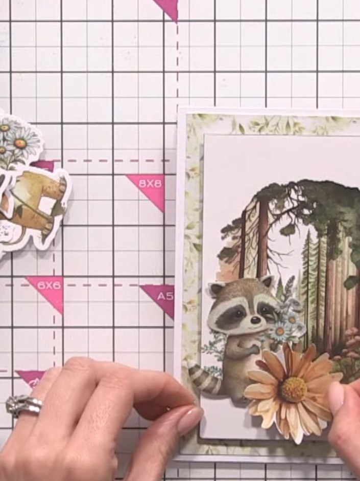 Step 13: Cut out leaf toppers from the kit and trim them down. Position the trimmed leaves at the bottom of the card to