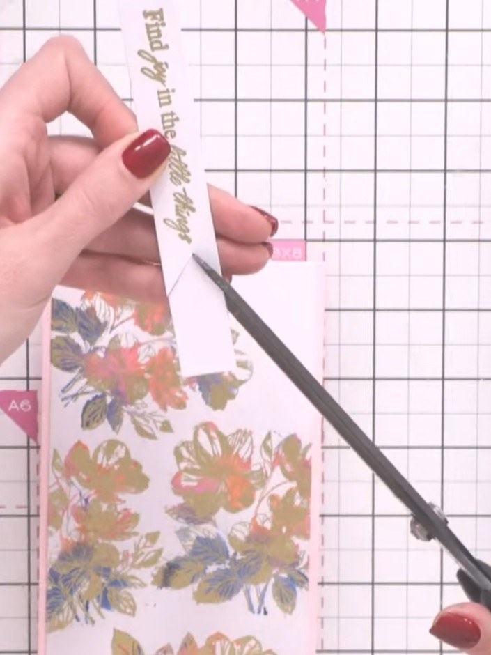 Step 9: Stamp your chosen sentiment from the stamp set onto a white banner strip using black ink. Position the sentime
