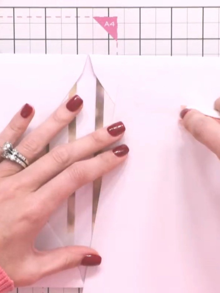 Step 6: Apply tape only to the top edge of the pink mat and layer. Do not tape the full perimeter, so the envelope ben