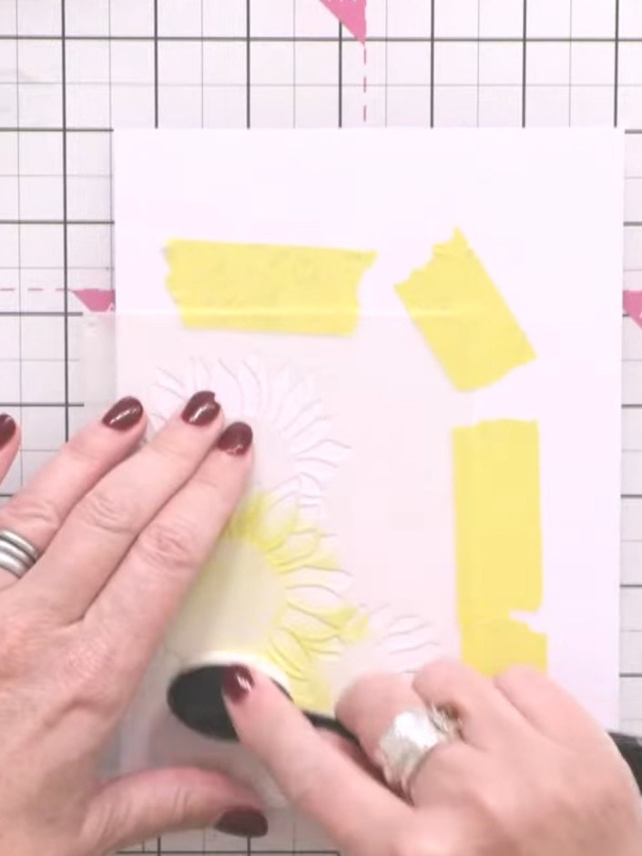 Step 1: Secure your card base with masking tape. Position the first layer of the Hope Blooms stencil over the card and